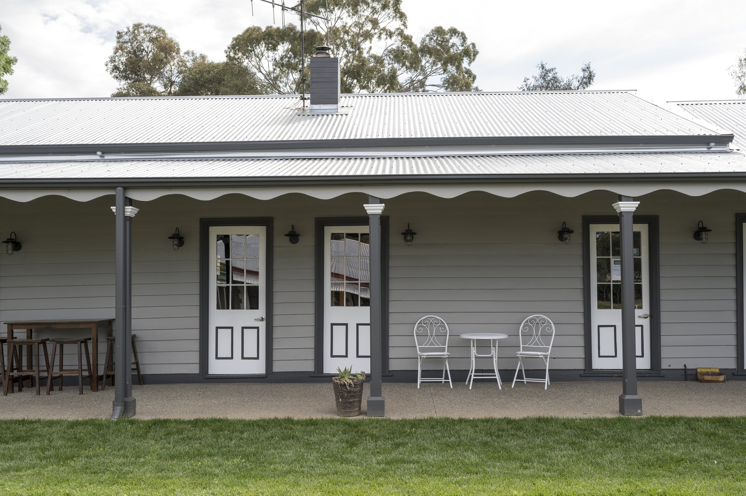 The quiet verandah of the Axedale Tavern, with lawn and white chairs