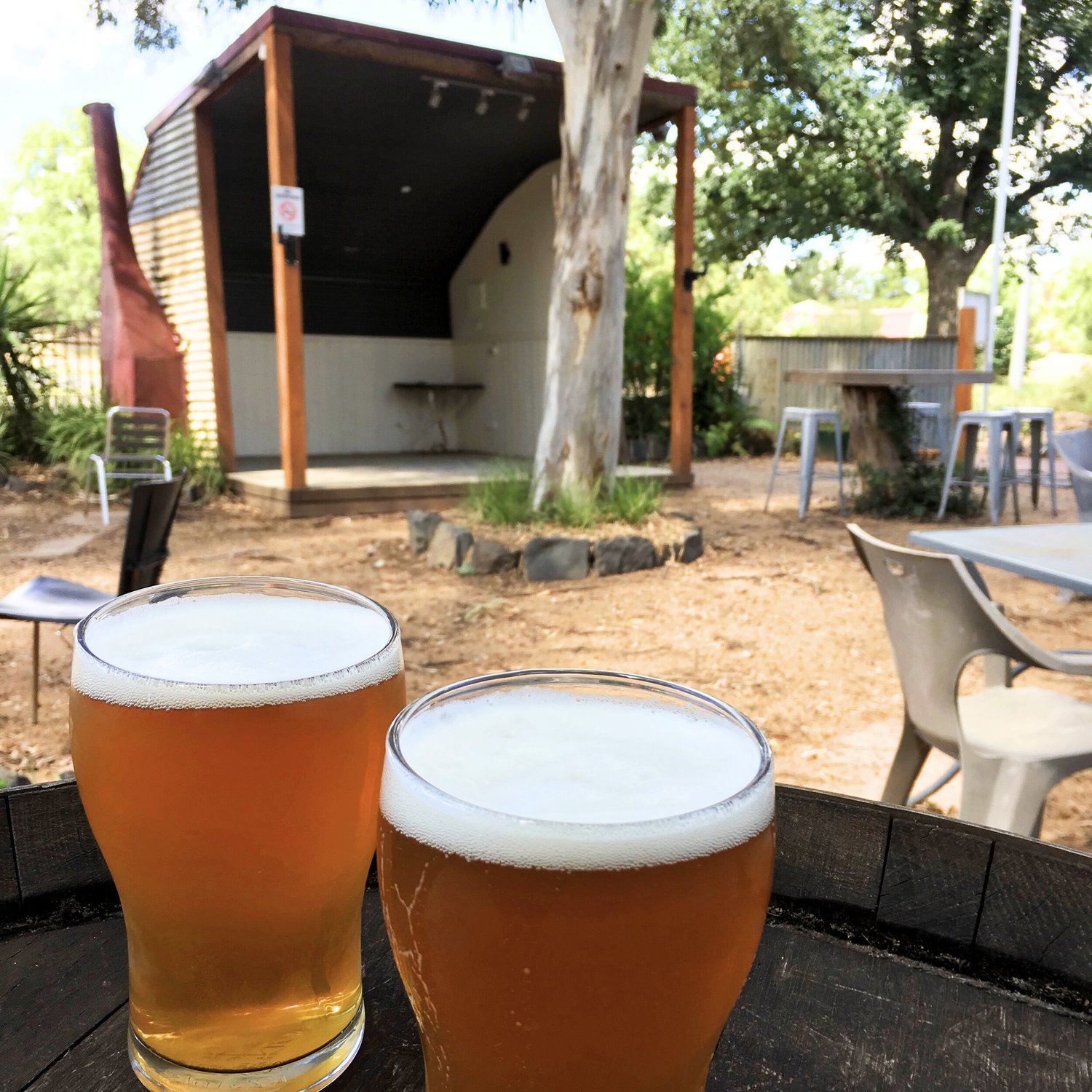 Two pots of beer with the tavern's little outdoor stage behind them