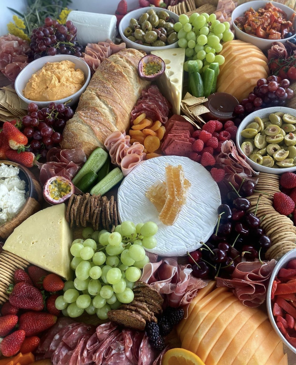 A large grazing board of cheese, fruit, bread and cured meat