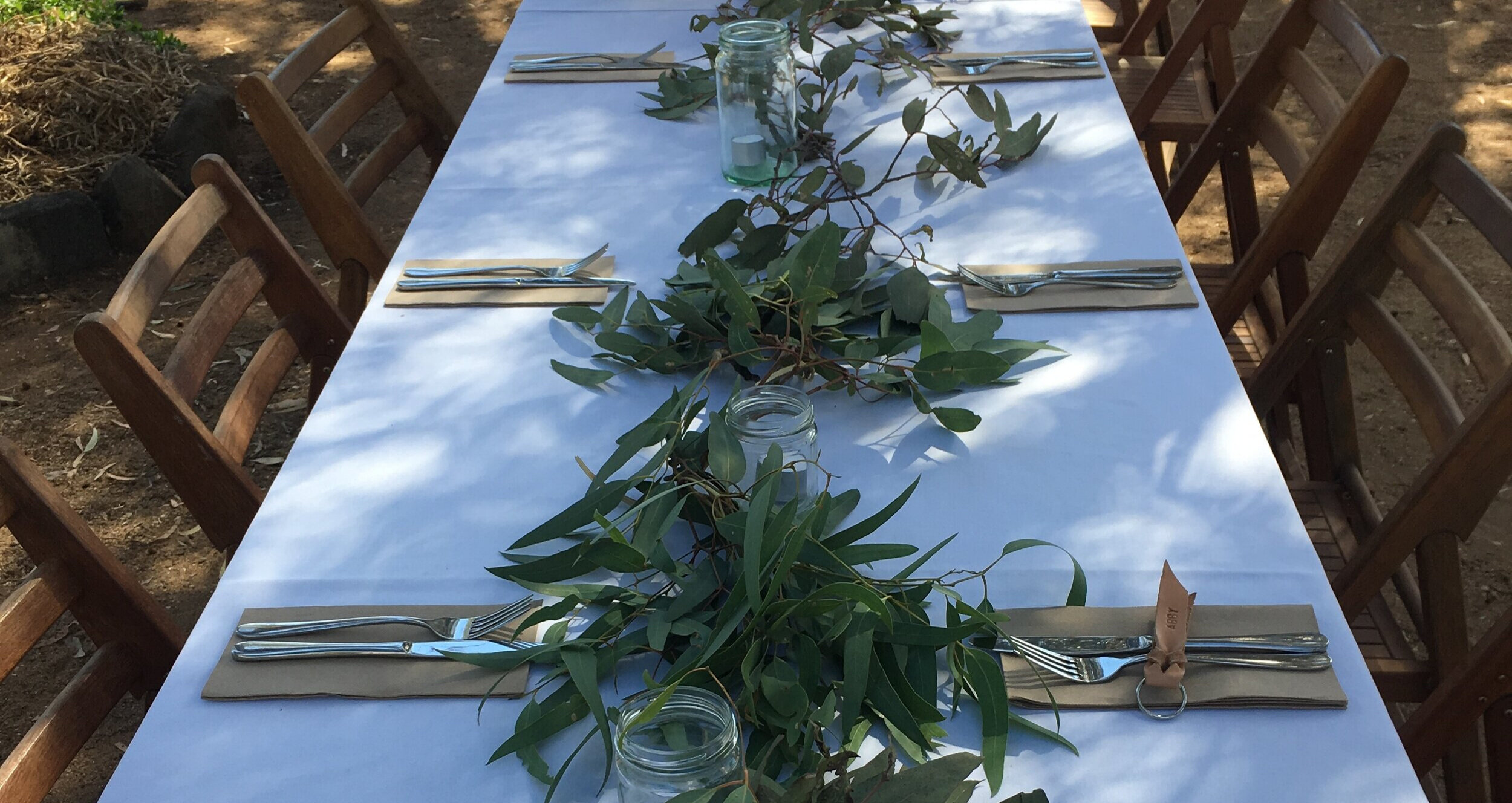 A long outdoor table set with gum leaves for a function at the tavern